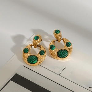 Gold plated stainless steel malachite earrings with hammered texture on newspaper background