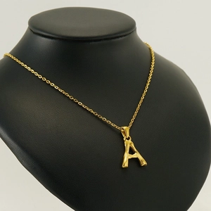 Elegant gold stainless steel necklace with letter A pendant on a black mannequin display