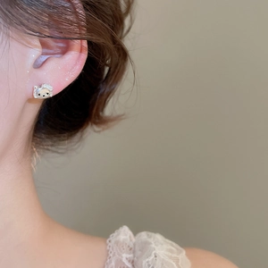 Macro shot of silver cat stud earring with zircon details worn on earlobe