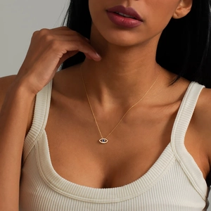Elegant gold necklace with blue Evil Eye pendant worn by a model in a close-up view