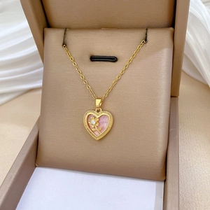 Close-up of gold heart pendant with pink pearlescent inlay and sparkling flower detail