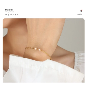 Detail of minimalist gold plated lip chain bracelet worn by a model on white sleeve