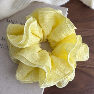 Close-up detail of oversized yellow ruffled scrunchie with layered fabric texture
