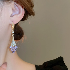 Detailed close-up of violet grape drop earrings with purple crystals on a model