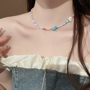 Close-up of colorful beaded necklace with starfish and daisy charms on a model