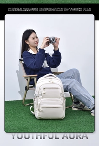 Detail of a cream student backpack with multiple pockets in an outdoor lifestyle setting