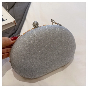 Close-up of silver glitter oval clutch bag featuring a sparkling rhinestone sphere clasp