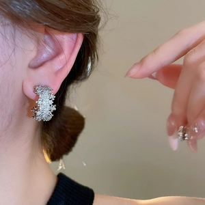 Close-up of a model wearing a silver C-shaped earring with zircon micro-pave details