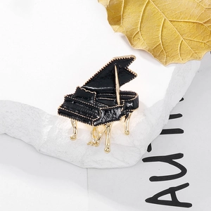 Vue détaillée d'une broche piano en émail noir et or sur une pierre texturée blanche