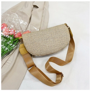 Detail of hand-woven straw crescent bag with brown adjustable strap and gold metal hardware