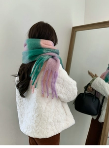 Detail of colorful plaid scarf with soft fringe and pastel gradient worn with white coat