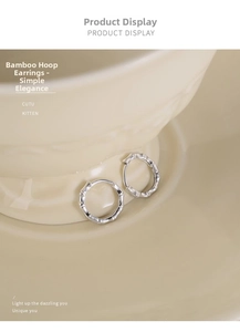 Close-up of minimalist silver bamboo-textured hoop earrings on a ceramic dish