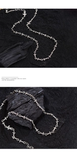 Close-up of vintage silver fleur-de-lis chain necklace on black charcoal background