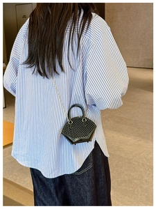 Black mini jelly crossbody bag with woven texture and gold chain on a model