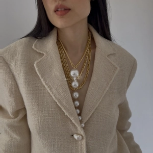 Close-up of multi-layer gold chain necklace with linear white pearl drop pendant on a model