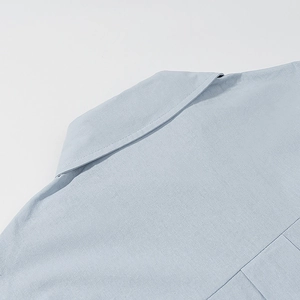 Detailed view of light blue linen shirt collar stitching and back yoke seam texture