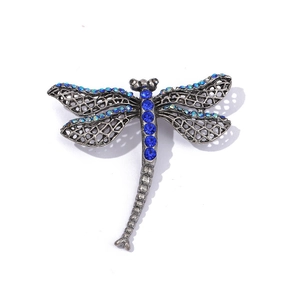 Close-up of vintage dragonfly brooch with blue crystals and intricate cutout wings