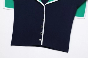 Close-up of navy knit cardigan with silver dome buttons and green contrast sleeves