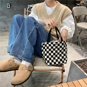 Detail view of a black and white checkerboard corduroy tote bag in a casual lifestyle setting