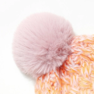 Close-up of the fluffy faux fur pom-pom and thick gradient knit texture on winter hat