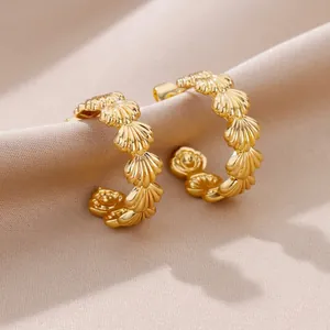 Elegant C-shaped golden shell texture hoop earrings on luxury beige silk fabric