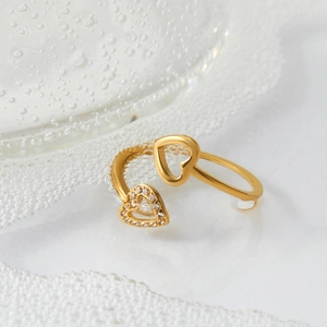 Bague ouverte double cœur dorée avec cristaux scintillants sur fond blanc épuré