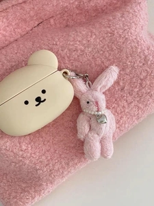 Detail of beige silicone headphone case with cute plush bunny and heart charm