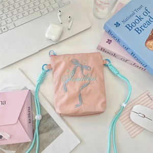 Vue détaillée du sac à bandoulière en toile rose avec nœud bleu clair brodé élégant