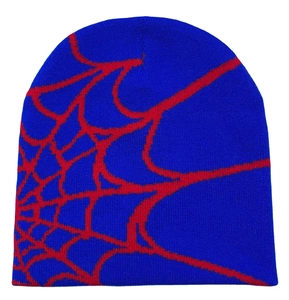 Macro detail of blue knitted beanie featuring a red jacquard spider web pattern texture