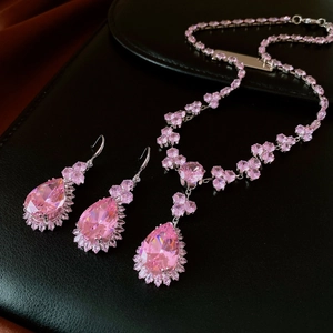 Detailed close-up of pear-cut pink crystal necklace and earrings set on black leather