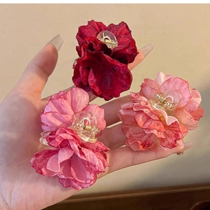 Detail of rose-shaped hair claw clips showing chiffon fabric petals and metal spring