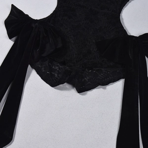 Close-up of black lace bodysuit featuring large velvet bow accents and intricate textures