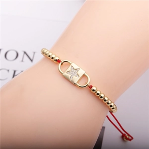 Detail eines roten Kordelarmbands mit Goldperlen und Zirkon-Sternplatte am Handgelenk