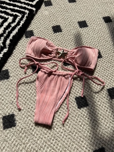 Pink ribbed bikini with starfish charm on geometric rug background with shadows