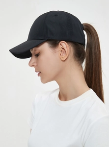 Side view of black ponytail baseball cap showing functional rear opening on female model