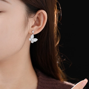 Close-up of elegant silver butterfly earrings with sparkling zircon stones on female model