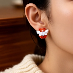 Close-up of a flocking brown bear earring with white wings and a sparkling gemstone