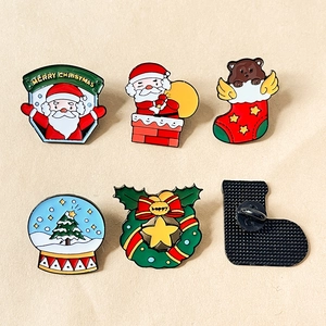 Set of six Christmas enamel pins featuring Santa Claus and reindeer on a beige background