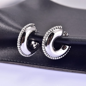 Detailed close-up of silver-tone hoop earrings with sparkling zircon inlay and polished finish