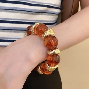 Detail of amber acrylic beads and polished gold metal spacers on a beaded bracelet