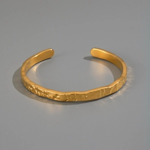 Gros plan d'un bracelet jonc en acier plaqué or 18K avec texture martelée