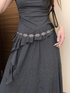 Detail of vintage silver oval chain belt styled on a grey slim-fit ruffled dress