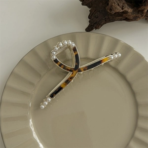 Detail of golden metal hair claw with tortoiseshell texture and small pearl accents