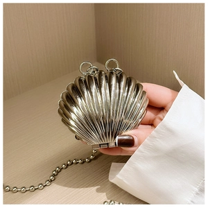 Detail of shell-shaped mini metal evening bag with gold texture and beaded chain strap