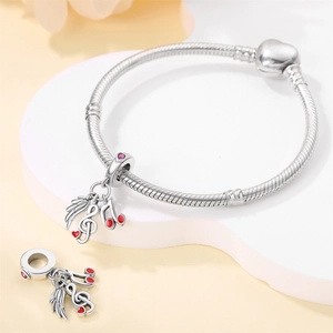 Detailed view of a silver music note wing charm with red heart gems on a heart-clasp bracelet