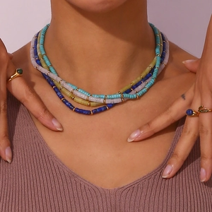 Detail of multilayer beaded necklaces in blue, pink and green with gold accents