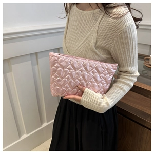 Macro detail of pink quilted heart pattern cosmetic pouch with silky glossy finish