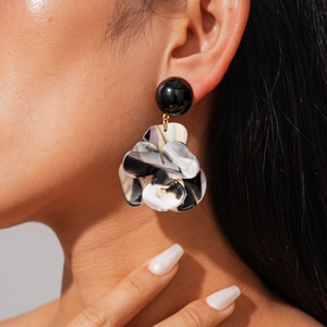 Macro view of resin flower drop earrings with marble texture on female model ear