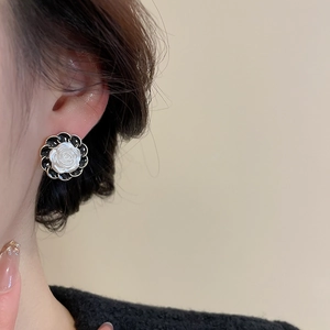 Detail of vintage French style black and white rose earrings with gold metal trim edges