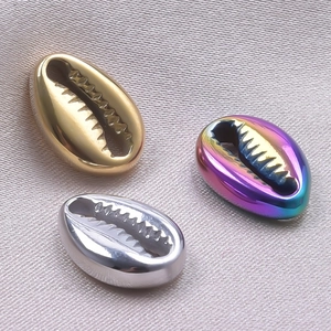 Macro shot of seashell-shaped stainless steel charms in gold, silver, and rainbow plating